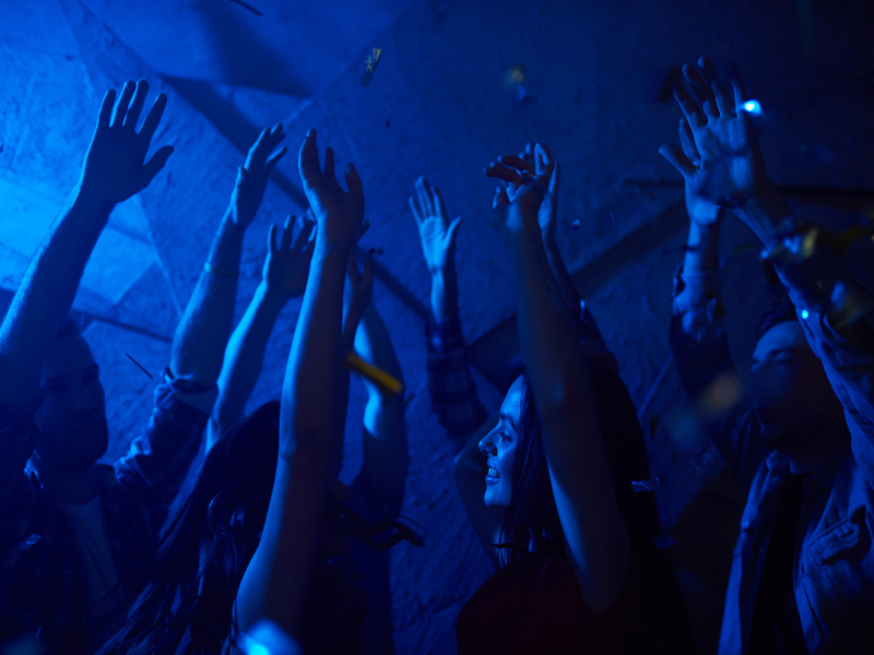 Des amis dansent avec les mains levées dans un club