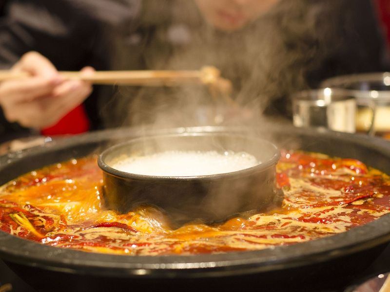 Les hotpots sont un plat de base de la culture alimentaire chinoise. Ici, une image montre un hotpot avec une sauce épaisse et un bol de riz au centre.