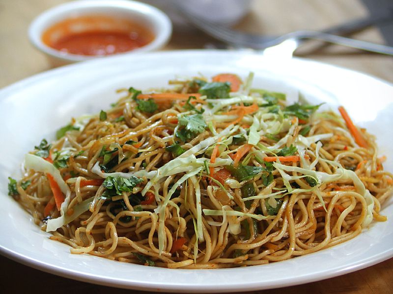 Le chow mein est un plat clé de la culture alimentaire chinoise. Cette image montre un chow mein de légumes avec des carottes râpées, du chou et des nouilles dans un bol blanc.