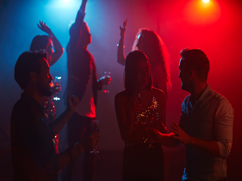 Des amis joyeux avec des flûtes discutent lors d'une fête dans une boîte de nuit.