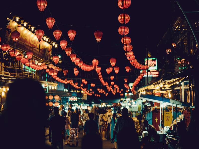 Le Vietnam est-il cher ? Des gens marchent entre des étals de nourriture de rue.